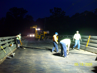 Back-hoe and Highway personnel working on bridge at night under lights