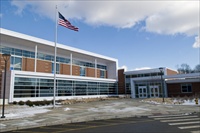 Center School with American Flag in front taken from parking lot so large wide sidewalk infront of school entrance is showing in foreground