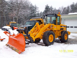 Tractor with plow attachment on front pushing snow