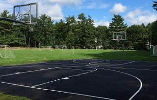 Basket ball court with two hoops and a field behind with many soccer nets
